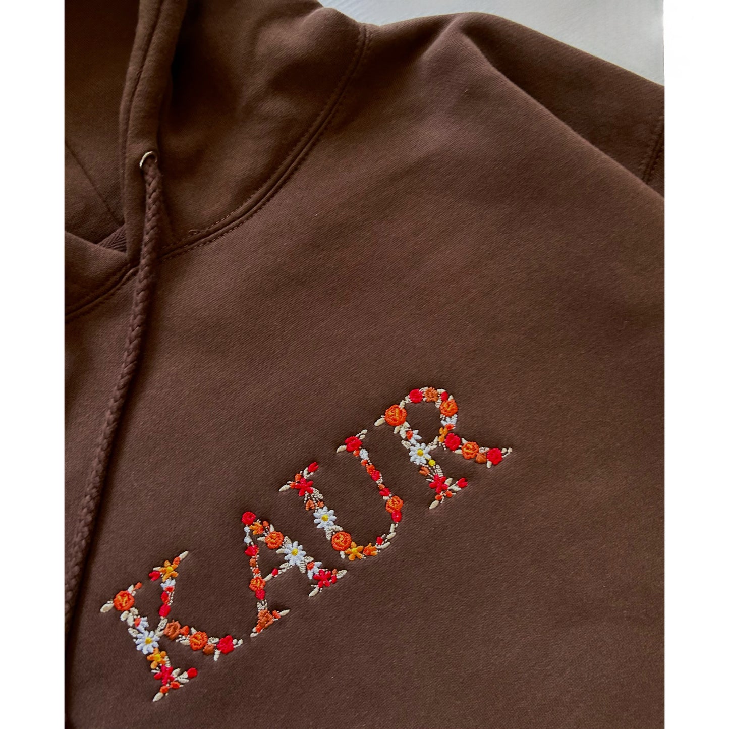 KAUR Hoodie Embroidered
KAUR hoodie with floral design on chest, artistic embroidery on dark fabric, Sikh-inspired apparel for women, Punjabi hoodie, empowering Kaur sweatshirt